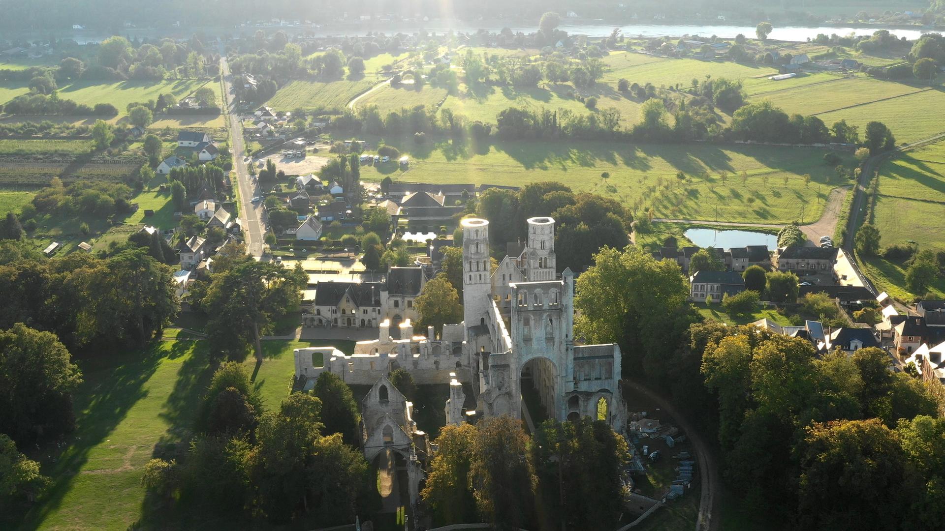 "Die Normandie - Frankreichs grüner Norden": Abtei in dörflicher Landschaft.