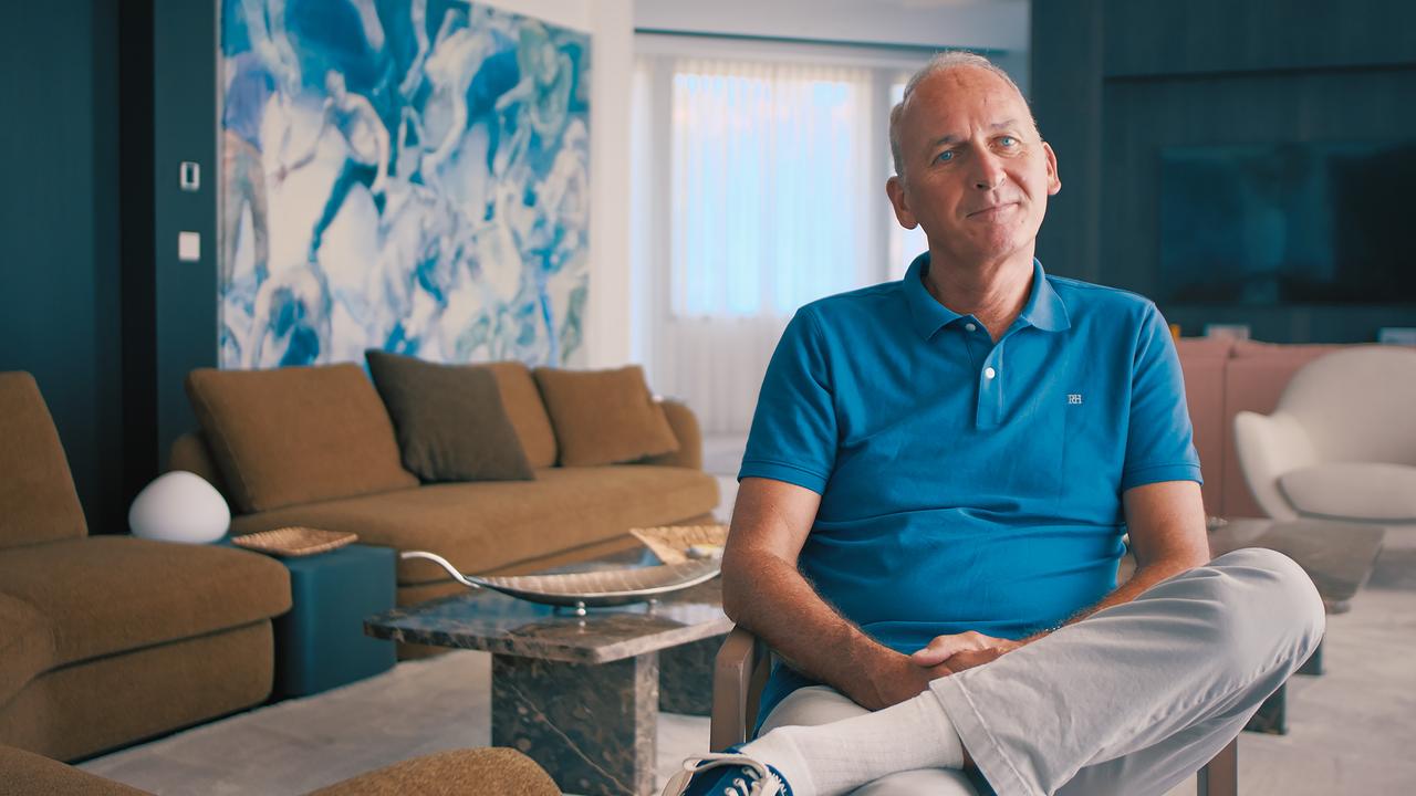 Mann in blauem Polohemd in hellem Wohnzimmer mit großem Bild an der Wand.