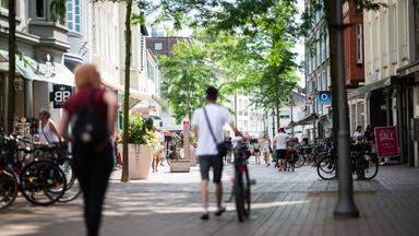 Menschen schlendern durch eine sonnendurchflutete Fußgängerzone