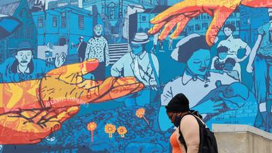 Frau läuft an Wandgemälde zur medizinischen Versorgung vorbei