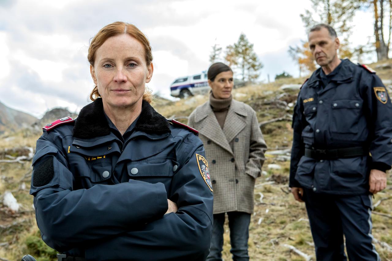 Dorfpolizisten zusammen mit der Oberinspektorin am Tatort in den Bergen.