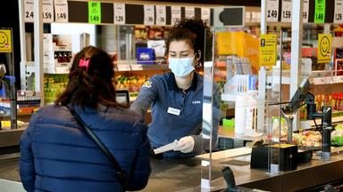 Kassiererin mit Mundschutz an der Supermarktkasse