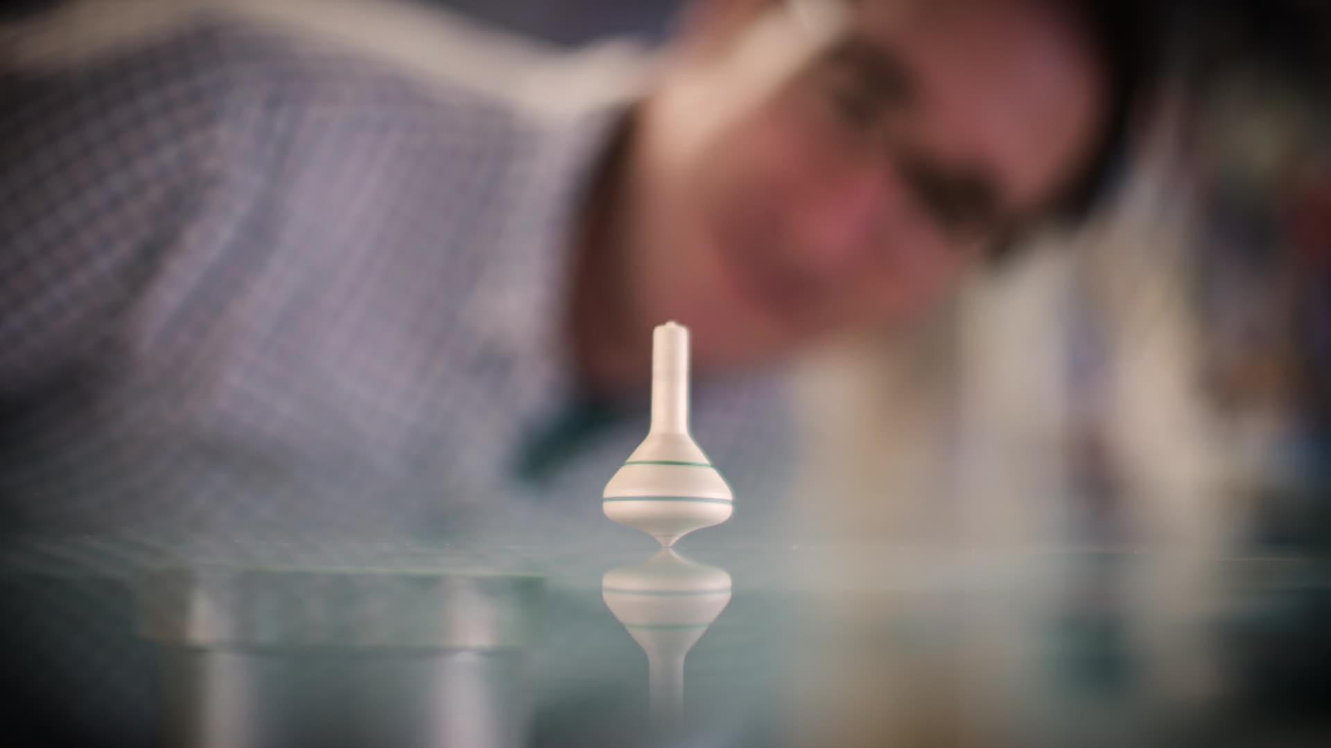 Im Vordergrund dreht ein Holzkreisel. Im Hintergrund beugt sich Physiker Martin Fertl darüber.