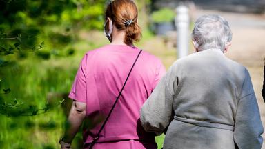 Krankenpflegerin mit alter Frau - von hinten