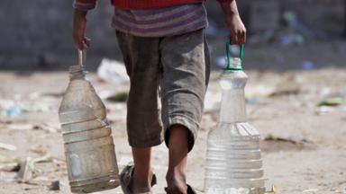 Junge schleppt Wasserkanister