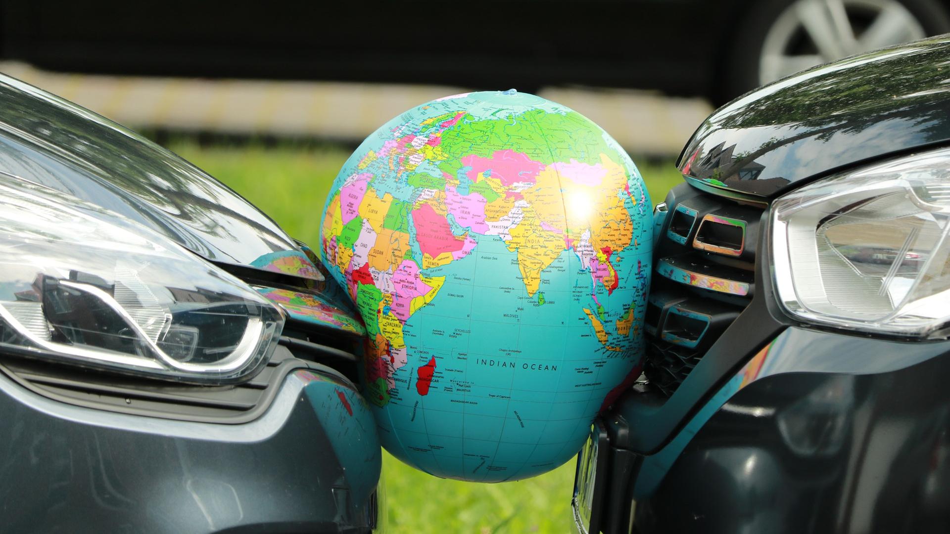 Autos zerwetschen einen Ball, der die Erde darstellt