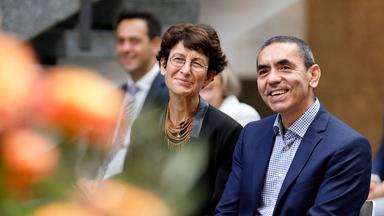 Sahin und Türeci bei Preisverleihung mit Lächeln im Gesicht und Blumen im Vordergrund des Bildes