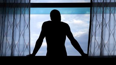 Dunkle Männersilhoulette an einem Fenster 