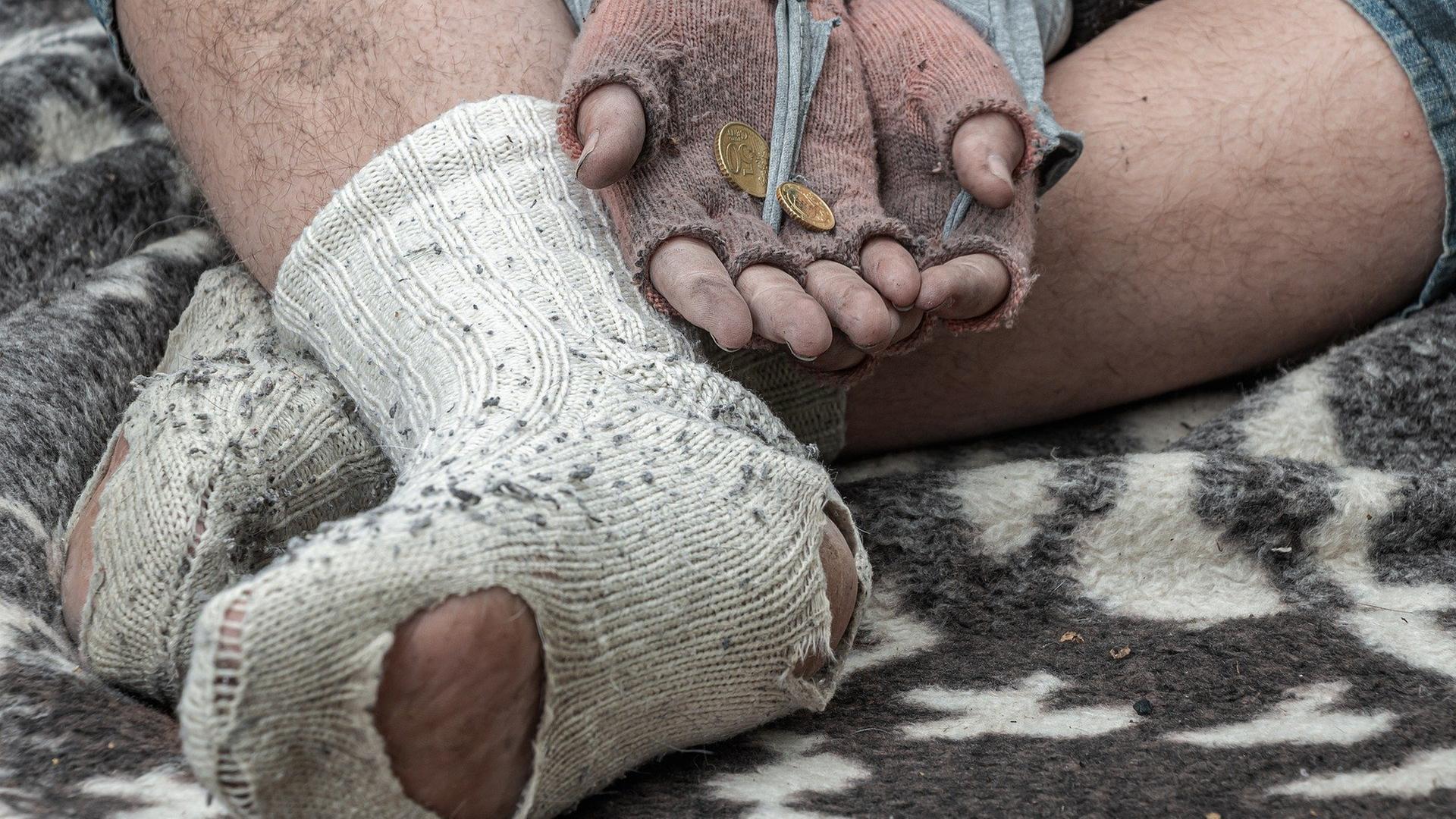 Füße und Hände eines Bettlers auf der Straße
