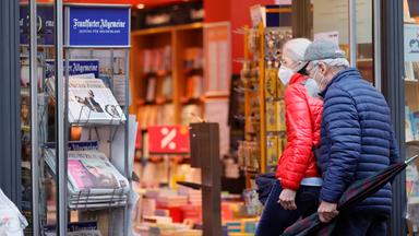 Menschen mit Maskeln vor einem Geschäft