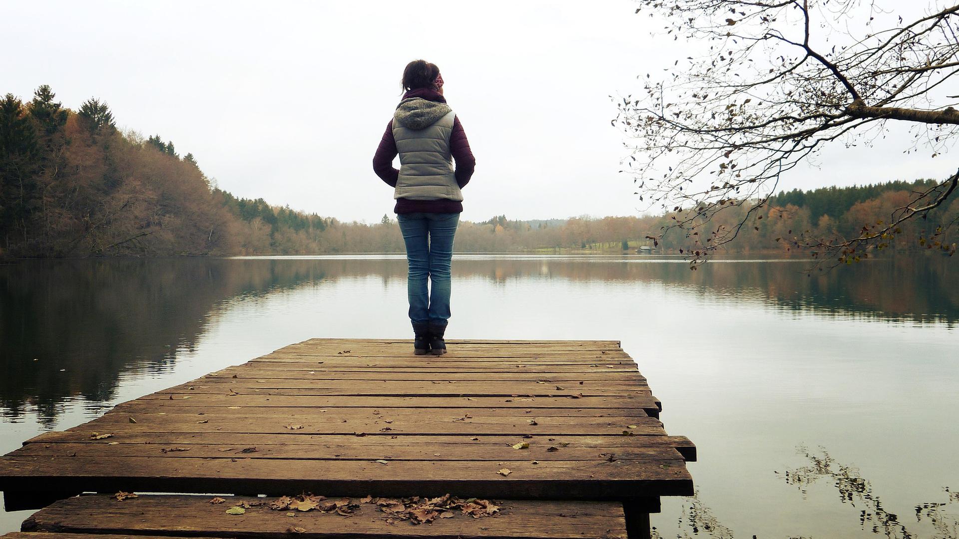 Frau von hinten SIe steht auf einem Steeg am Wasser