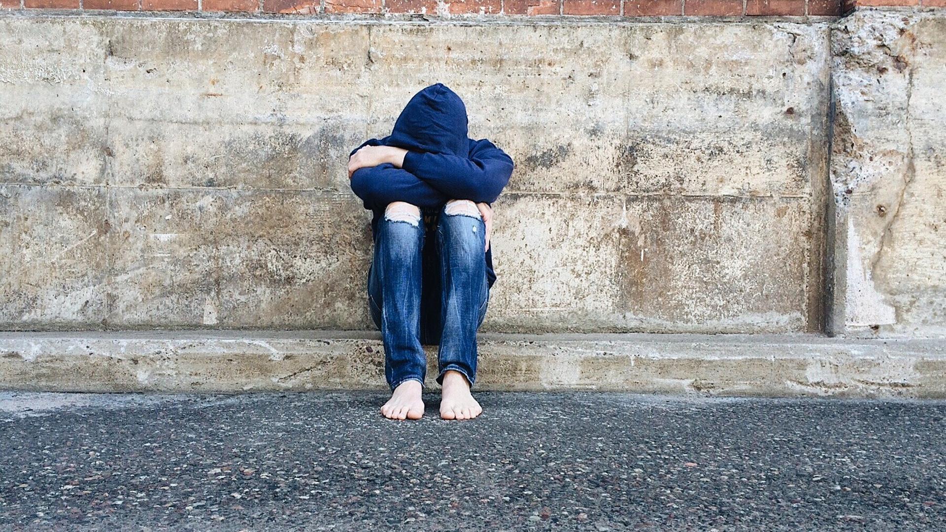 Ein Junge sitzt mit Kopf nach unten auf dem Boden