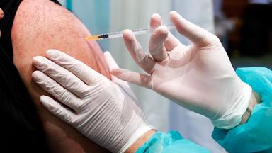 Maske mit darüberliegenden Impfspritzen