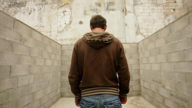 Jugendlicher steht in einem Raum, den Rücke zugewandt