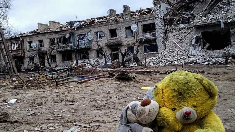 Schmutziger Teddybär vor zerstörtem Haus