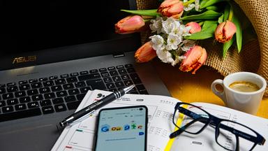 Homeoffice Arbeitsplatz mit Kalender im Vordergrund und Blumenstrauß