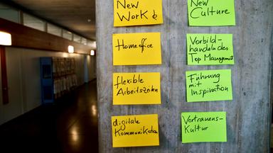  An einer Betonwand kleben Post-Its mit Stichwörtern in verschiedenen Farben.