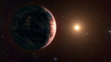 Eine Computeranimation zeigt einen fremden Planet in einem fremden Planetensystem. Seine Atmosphäre schimmert rötlich.