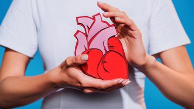 Symbolbild: Frau halt ein Papierherz in der Hand