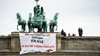 Klimaaktivisten auf dem Brandenburger Tor, ein herunterhängendes Banner im Vordergrund