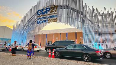 Logo Klimakonferenz, im VOdergrund Menschen