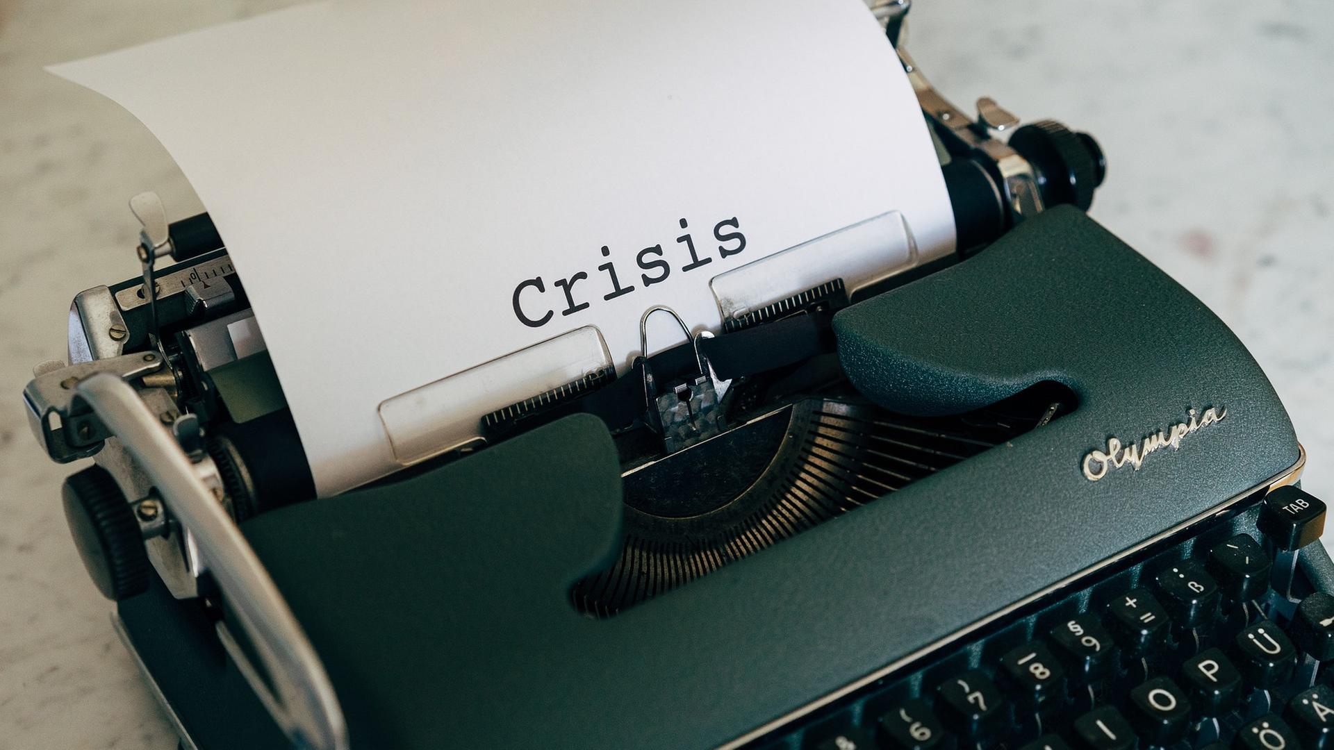 Schreibmaschine mit Papier mit der Aufschrift "Crisis"
