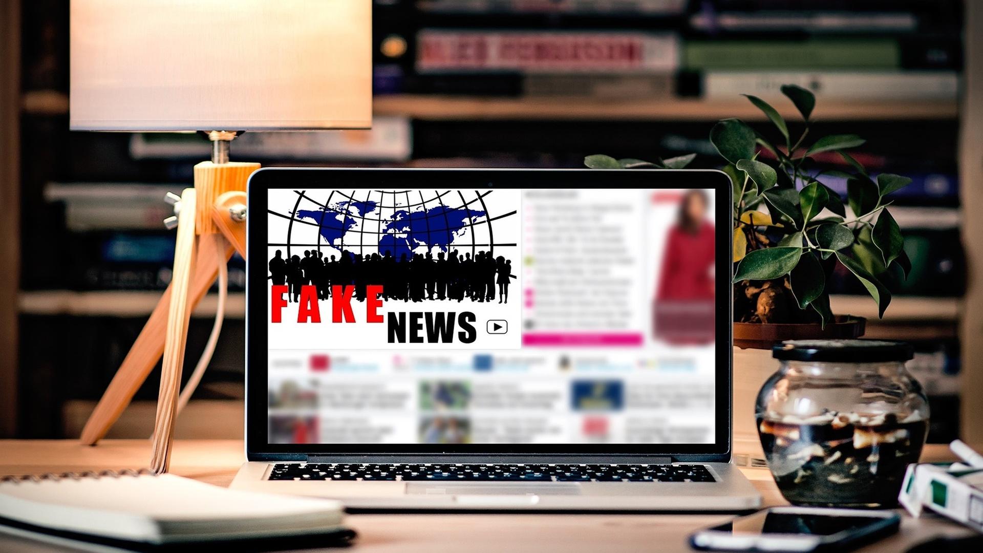 Laptop auf einem Schreibtisch. Zu sehen auf die  Bildschirm die Aufschrift "Fake News"