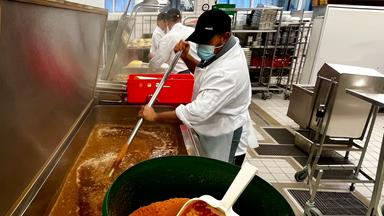 Koch rührt Saucenpulver in Großküchen-Tank.