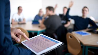 Tablet, im Hintergund Schüler in einem Klassenzimmer