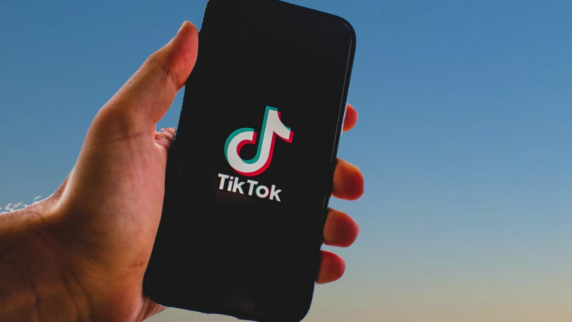 Handy mit Schriftszug TikTok in einer Hand