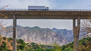 Lastwagen auf einer Brücke, im Hintegrund Berglandschaft