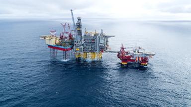 Förderplattform für Öl und Gas umgeben von den Weiten der Nordsee. Darüber bleiern bewölkter Himmel bis zum Horizont.