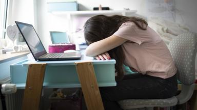 Müdes KInd schläft am Schreibtisch