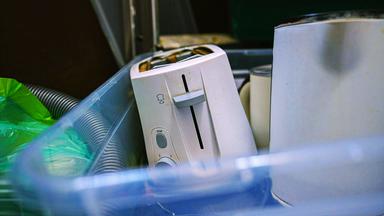 Defekter weißer Toaster liegt in Plastikkiste