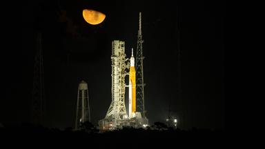 Nachtaufnahme der hell angestrahlten neuen Mondrakete SLS, die vor dem Start auf der Startrampe steht