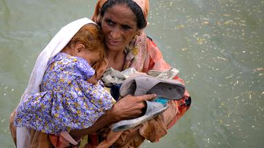 Frau mit Kind in Hochwasser in Pakistan