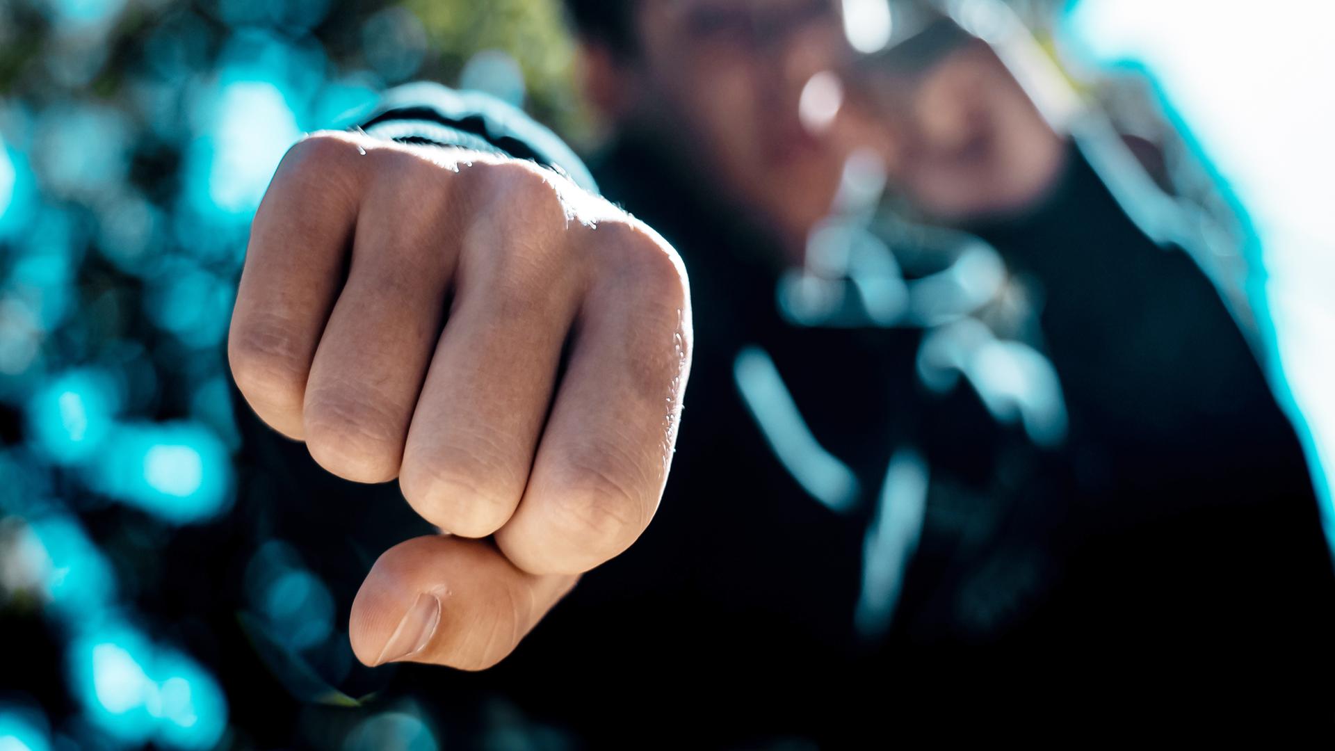 Blick von unten auf die geballte Faust eines jungen Menschen.
