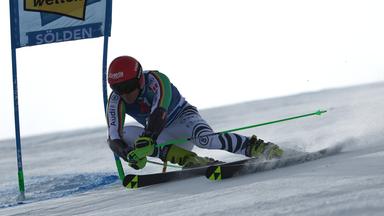 Skirennfahrter umfährt eine Fahne auf der Piste