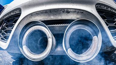 Abgase entweichen aus zwei großen Auspuffrohren eines Autos.