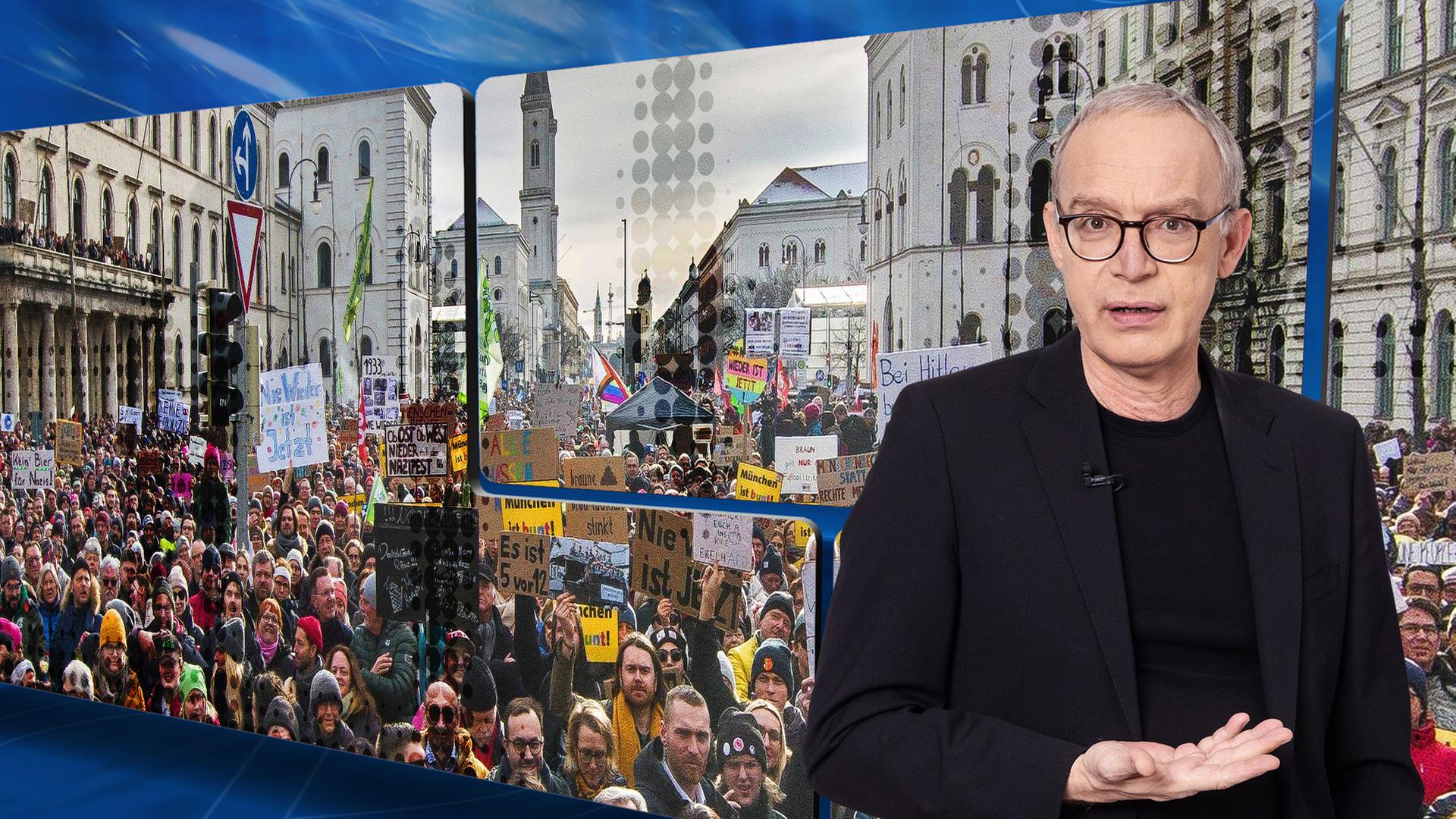 Der Moderator vor einer Videowand, auf der die Münchner Demo gegen die AfD vom 21. Januar zu sehen ist.