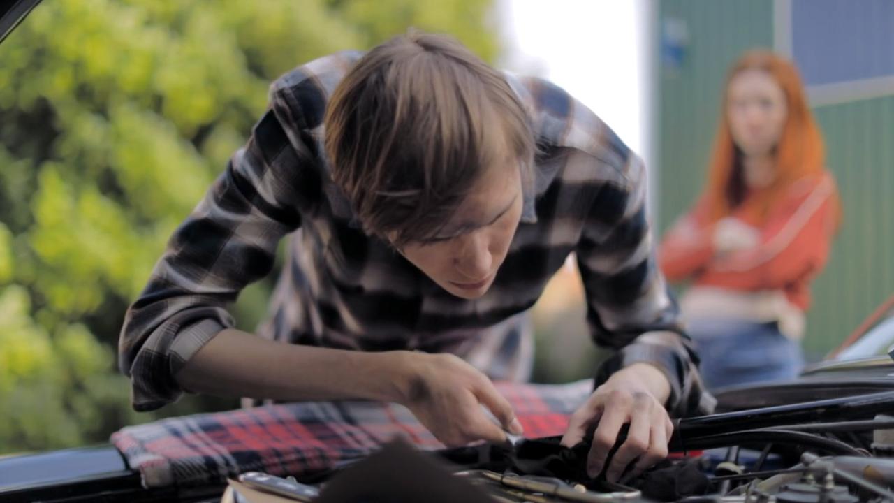 Mann beugt sich in den Motorraum