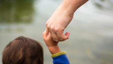 Frau hält Kind an der Hand