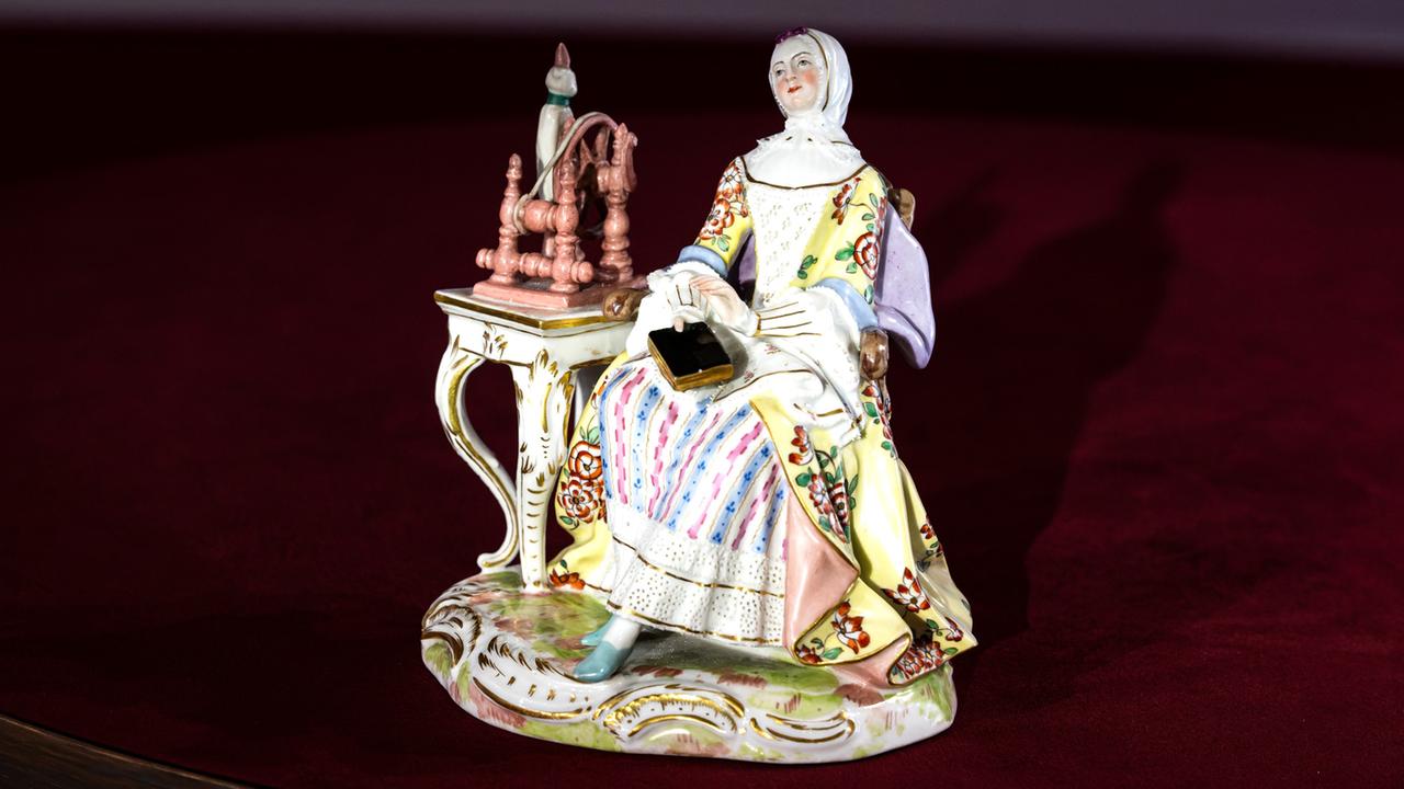 Eine Porzellanfigur einer Dame am Spinnrad