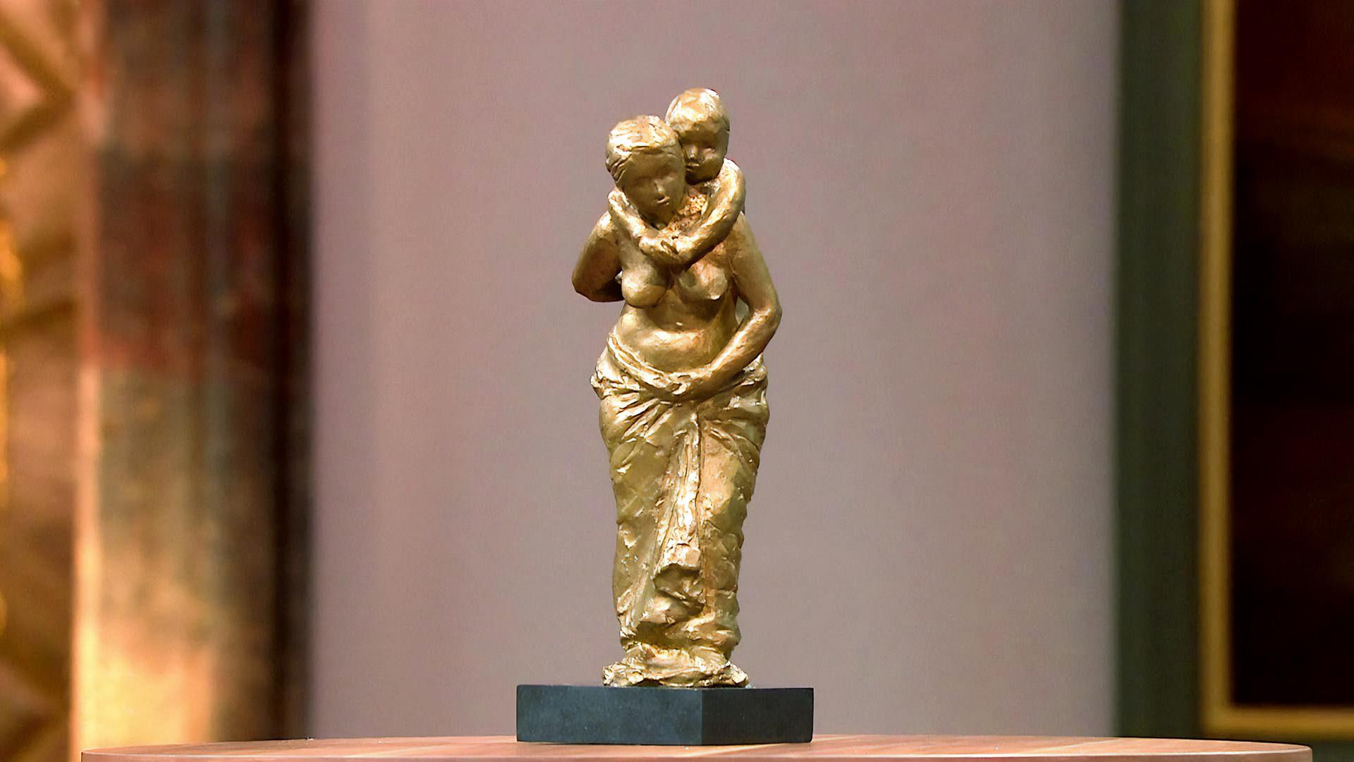 Eine Bronzestatue einer Frau, die ein Kind auf dem Rücken trägt.