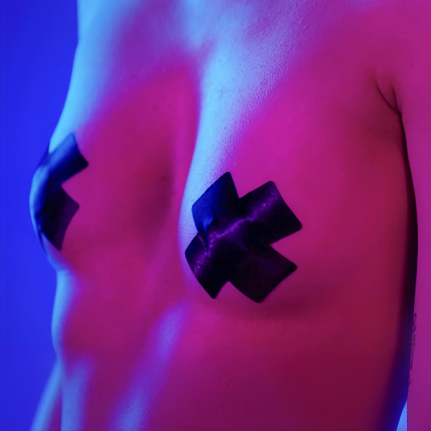 Nackter Oberkörper einer Frau. Die Nippel sind mit Klebeband in Form eines „x“ abgeklebt. Blau-pinke Farbstimmung.