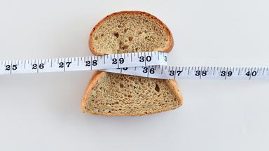 Eine Scheibe Brot, die mit einem Maßband umwickelt ist.