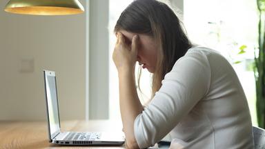 Frau sitzt erschöpft an Tisch