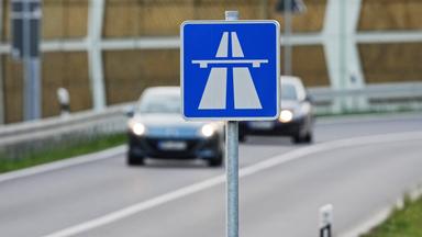 Autobahnschild, verschwommene Straßenansicht in Hintergrund
