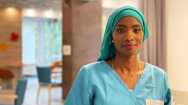 Eine junge Frau in Pflegekleidung.