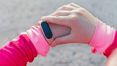 Frau schaut  auf ihren  Fitness Tracker am Handgelenk